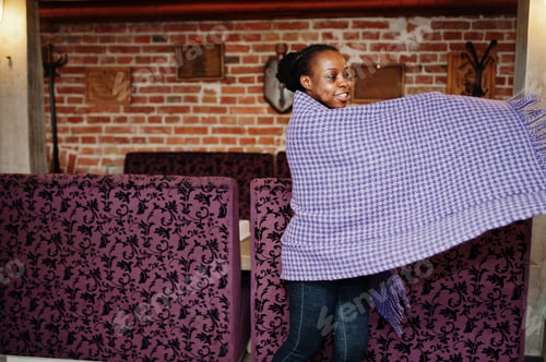 Preview: African woman in checkered violet cape posed at cafe.