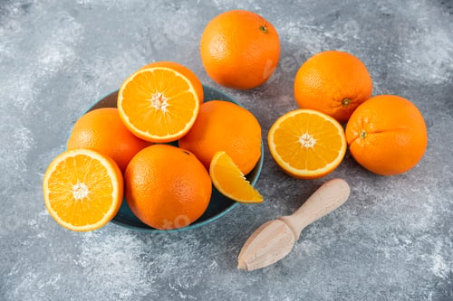 Preview: A bowl full of sliced and whole juicy orange fruits with wooden reamer