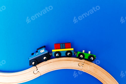 Preview: Colourful wooden toy train on blue background with copy space