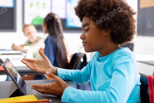 Preview: Happy diverse schoolchildren sitting at desks in school classroom