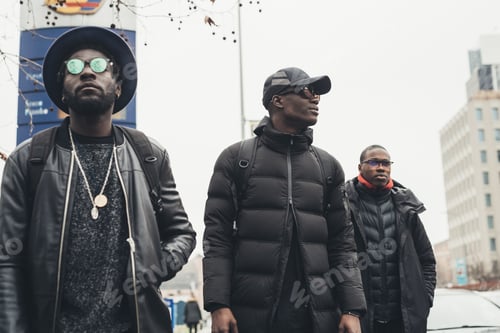 Preview: three young black men walking in the street and looking further