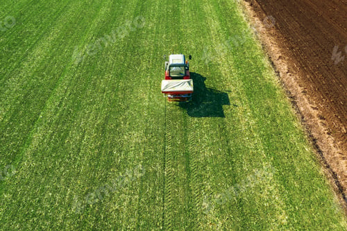 Preview: Agricultural tractor fertilizing wheat crop field with NPK
