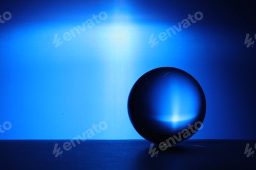 Preview: Transparent glass ball on table against blue background. Space for text