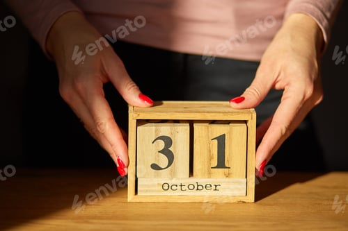 Preview: Woman hand change, sets the date on the wooden calendar on 31 October
