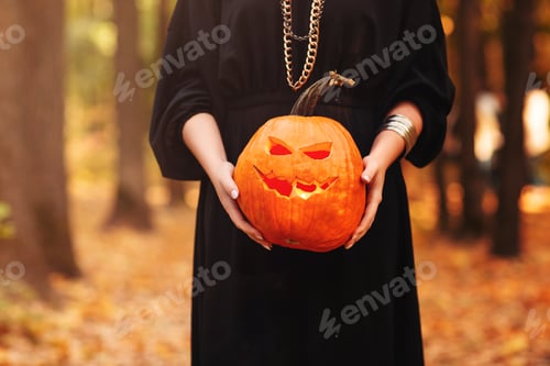 Preview: Young witch with jack o lantern in forest