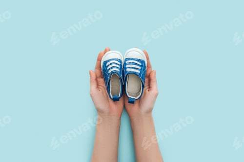 Preview: partial view of adult man holding sneakers on blue background with copy space