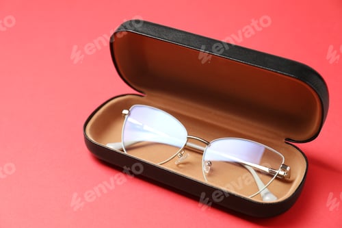 Preview: Case with stylish glasses on red background, closeup