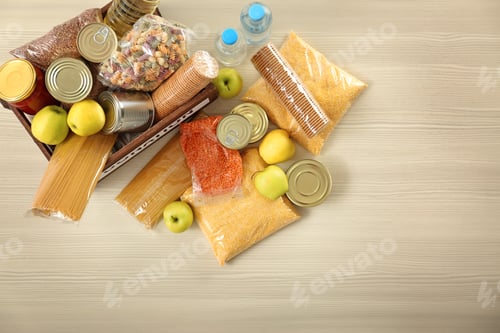 Preview: Donation box and different products on wooden table, top view. Space for text
