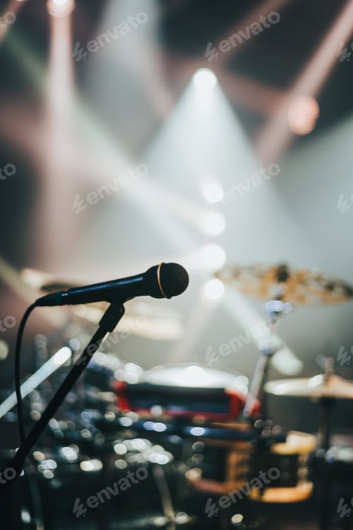 Preview: Microphone standing on a stage with a drum set in the background