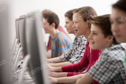 Preview: A group of young people, boys and girls, working at computer screens in class.