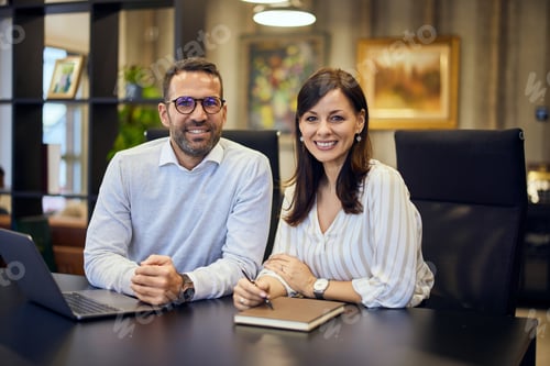 Preview: Portrait of a smiling businesswoman and businessman working on the same project at the office.