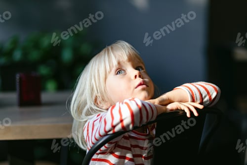 Preview: blond child sitting on a chair near the table