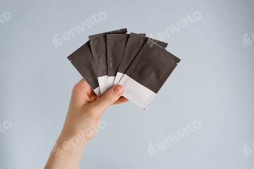 Preview: Disposable Bags with Cosmetics in a Woman's Hand on a Blue Background
