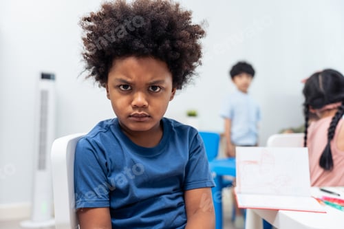 Preview: Portrait of Stressed African black child boy sitting in classroom.