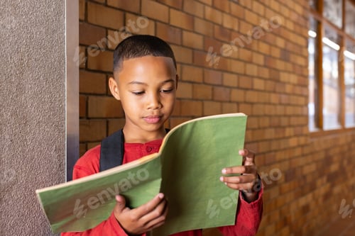 Preview: Reading notebook, boy standing in school hallway with backpack on