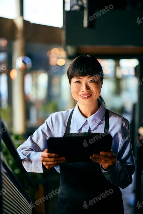 Preview: Asian Businesswoman Holding a Tablet at a Modern Indoor Workspace Environment