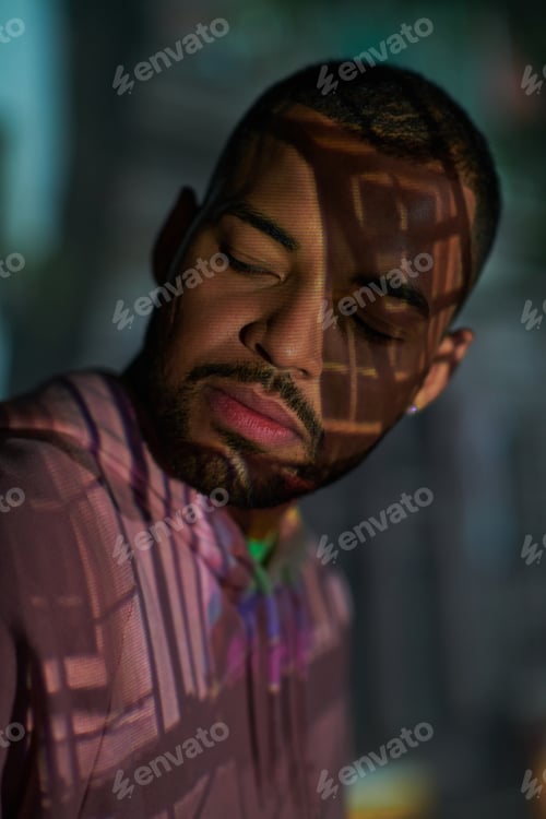 Preview: portrait of young stylish man with beard looking away in digital projector lights, fashion concept