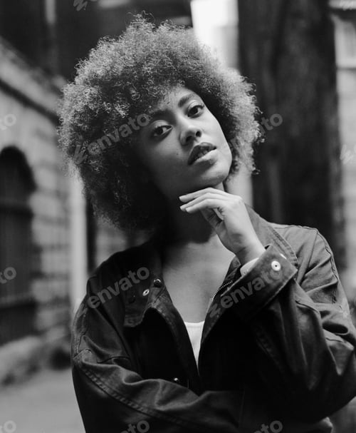 Preview: Monochrome portrait of intense young woman looking at camera outdoors.