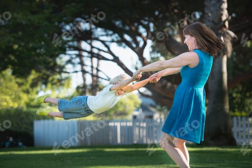 Preview: Mother swinging son around, outdoors