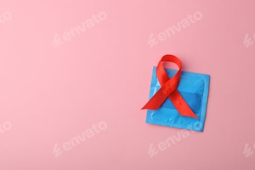 Preview: Red Ribbon On Condom Isolated On Pink Background. Stop Free Sex For Aids Prevention Campaign.