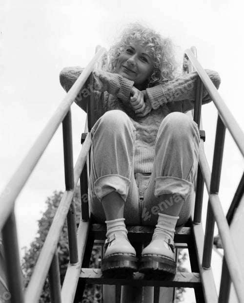 Preview: Low point of view of funny woman sitting on slide ladder.