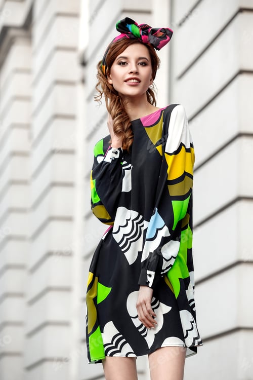 Preview: Slim beautiful girl in a stylish colorful summer dress and a bandana on her head is standing in a
