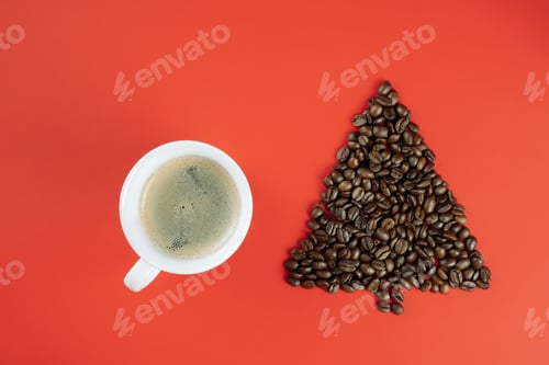 Preview: Brown coffee beans laid out in shape of Christmas tree with cup of coffee on red background. Flat