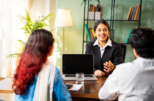 Preview: Indian professional executive meeting young couple in modern office with laptop for a deal