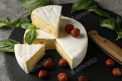 Preview: Tray with camembert, hazelnut, basil and knife on gray background