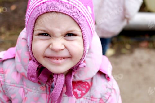 Preview: A cute girl in a hat smiles, wrinkling her eyebrows.
