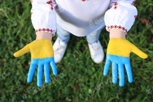 Preview: Little girl with hands painted in Ukrainian flag colors outdoors, top view. Love Ukraine concept