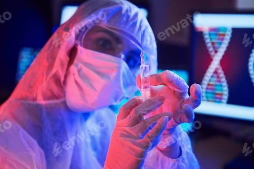 Preview: Nurse in mask and white uniform, holding syringe and sitting in neon lighted laboratory