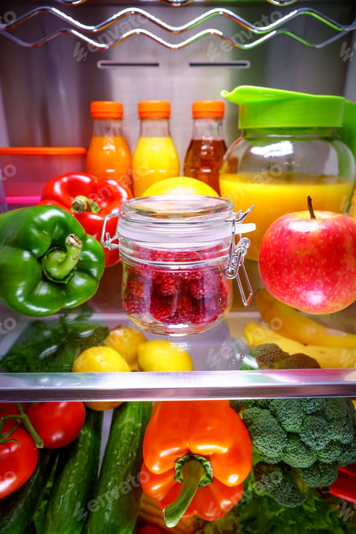 Preview: Fresh raspberries in a glass jar on a shelf open refrigerator