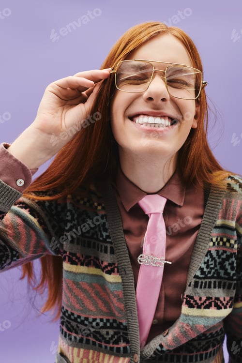 Preview: Fashionable young man with long red hair joyfully posing against a vibrant purple background
