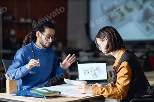 Preview: Young Caucasian Woman Collaborating with Young Black Man on Architectural Project