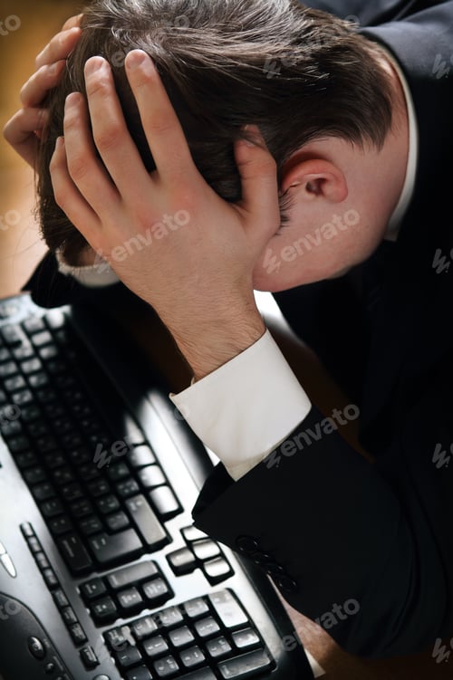 Preview: Depressed business man sitting at workplace and grieving