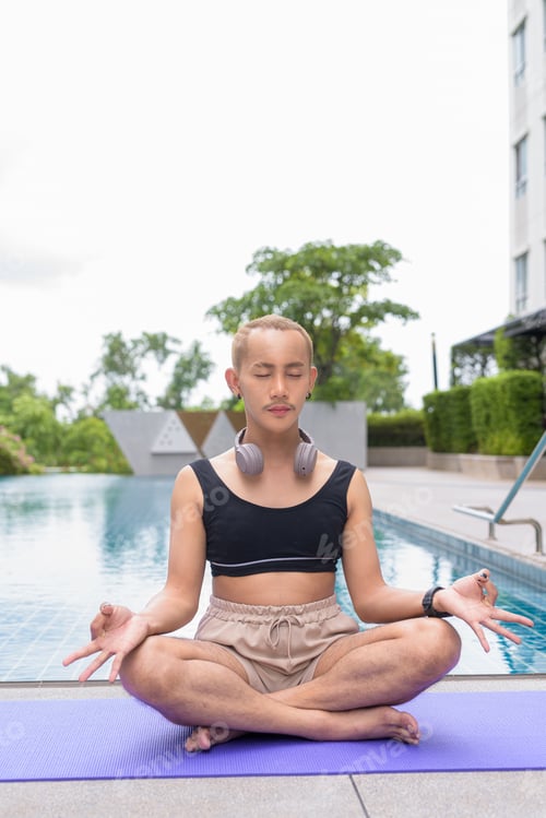 Preview: Non-binary person exercising in poolside doing yoga and wearing sport bra