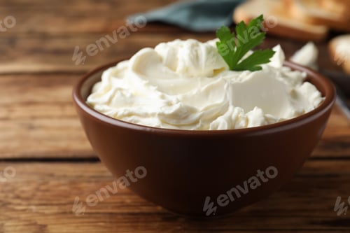 Preview: Bowl of tasty cream cheese and parsley on wooden table, closeup