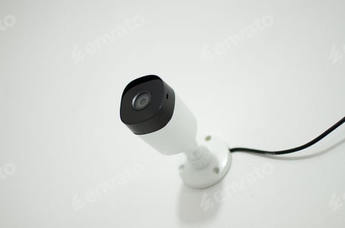 Preview: Close-up of a security camera mounted on a wall in a modern office, ready to be used