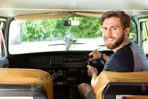 Preview: Man sitting in vintage camper van driver seat adjusting clip-on fan while looking back, copy space