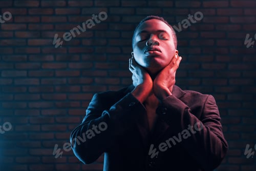 Preview: Futuristic neon lighting. Young african american man in the studio