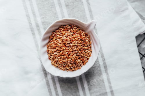 Preview: Flaxseeds in a white bowl on a linen tablecloth at home kitchen