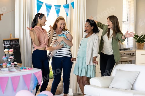 Preview: Women celebrating baby shower with cupcakes and decorations in cozy living room