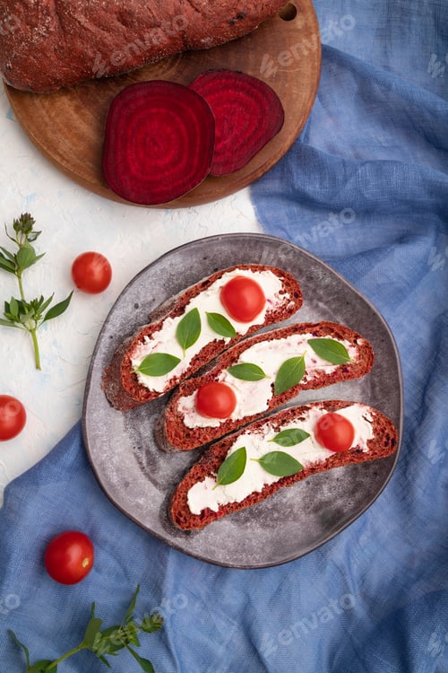 Preview: Red beet bread sandwiches with cream cheese and tomatoes on white concrete background