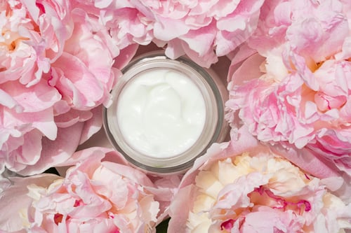 Preview: "Opened skincare jar with velvety cream exposed beside dewy peonies, inviting touch.