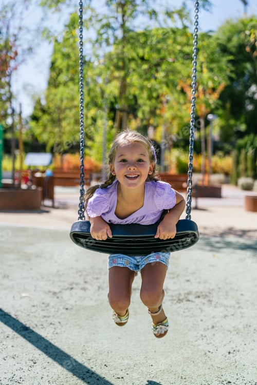 Preview: Young girl laughing swinging in urban park playground