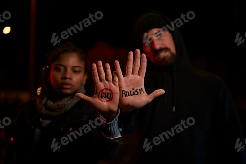 Preview: A young white man and a young black woman displaying a handwritten message against racism.