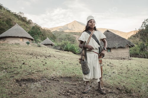 Preview: An indigenous Arhuaco man in traditional dress smiles. We also see his village surrounded by nature