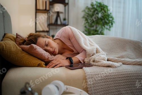 Preview: Woman sleeping in bed wearing activity tracker