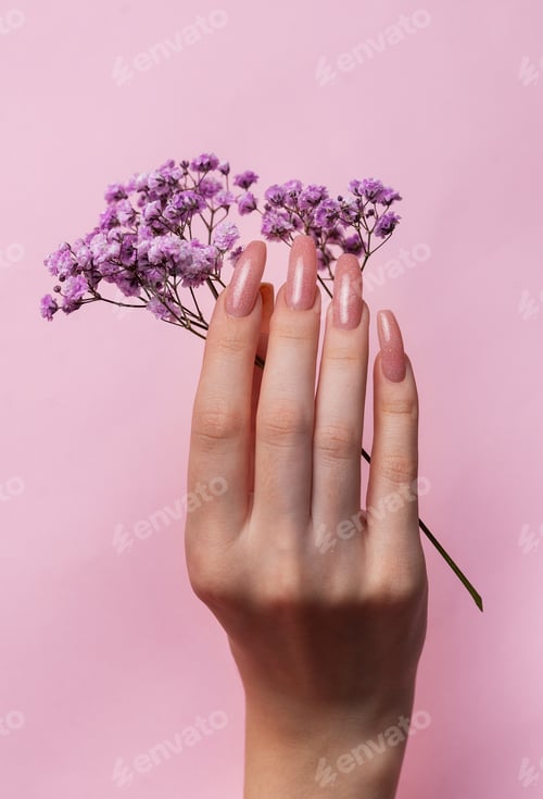 Preview: Female hands with pink nail design hold gypsophila flowers.